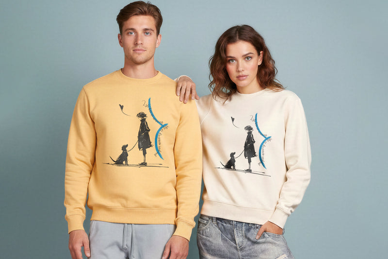 A male and female model wearing the Meaningful Life TOLS  sweatshirts in Nispero and Natural Raw, featuring an illustrative design with contrasting blue details, styled with casual denim and neutral trousers.